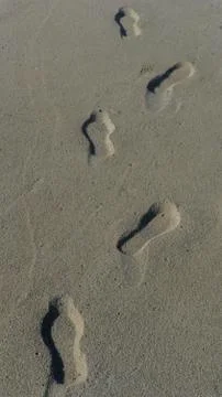 Beach scene of a path made with foot prints in sand Stock Photos