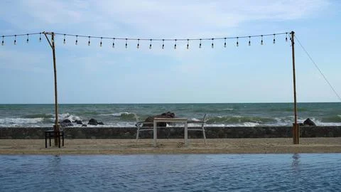 Beach scene with string lights, benches, and ocean view Stock Photos