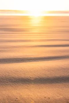 A beach scene with a sun setting in the background Stock Photos