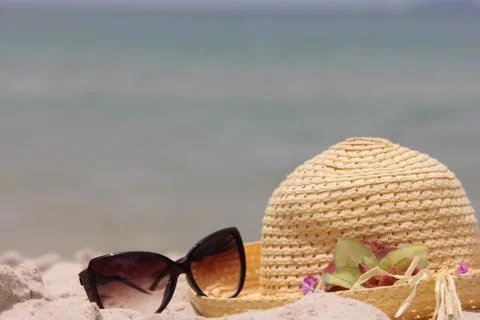 Beach scene. Sun straw hat and sunglasses lying on the sand on the beach Stock Photos