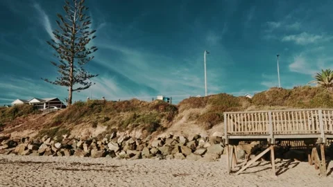 Beach Seaside Distant People Dune at Sunset with Wood Ramp and Moody Blue Skies Stock Footage 303731343