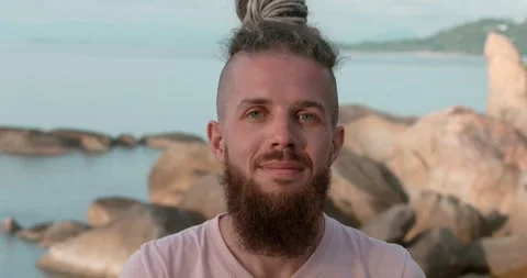 Beach setting man's confident look into camera rocks with sea at background Stock Footage 268600008