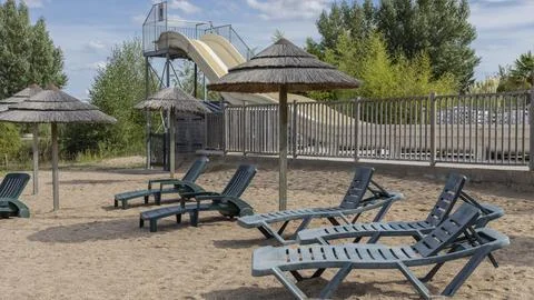 Beach by the side of a pool with water silde Stock Photos