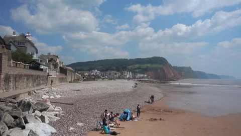 The beach at Sidmouth in Devon.  Pebbles and sand, tourists bask in sun Video stock 156186701