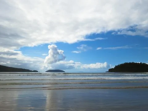 Beach with small waves on blue sky day and clouds. Stock Photos
