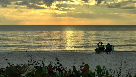 Beach at Sunset with 2 People Sitting on Seats Long Shot Stock Footage 88906465