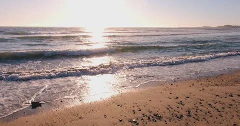 Beach at sunset, bright sunlight reflected on water. Pebbles lying on sand Stock Footage 135354936