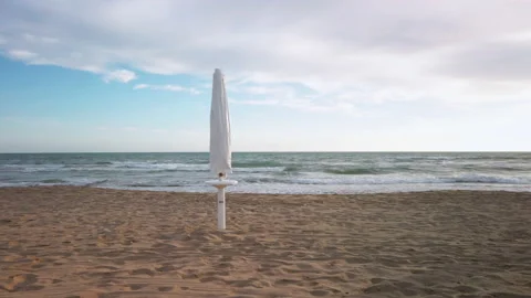 Beach at sunset with closed umbrellas. Rough sea Stock Footage 154314198