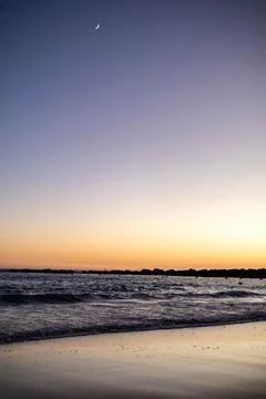 The beach at sunset with the moon in the sky Stock Photos