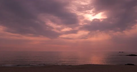 Beach at sunset with rays of sunlight shining through clouds onto ocean. Stock Footage 131683235