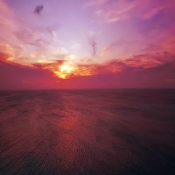 Beach sunset sun setting on the ocean horizon. Stock Photos