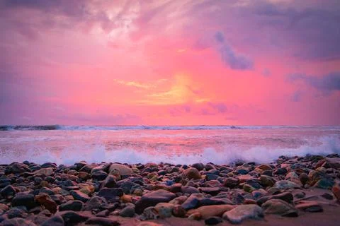 Beach sunset with waves breaking on shore Stock Photos