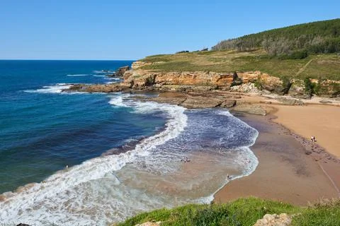 A beach surrounded by cliffs under a cloudless sky Stock Photos