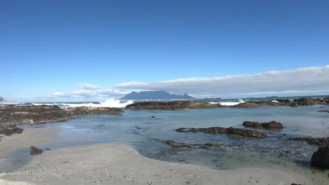 Beach surrounded by rocks pounded by the waves and views of Table Mountain Stock Footage 249325779