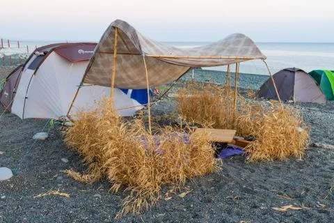 Beach tents on the beach with sand and stones, wooden table Stock Photos