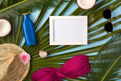 Beach theme on blue background. Beach accessories, palm leaves, photo frame o Stock Photos