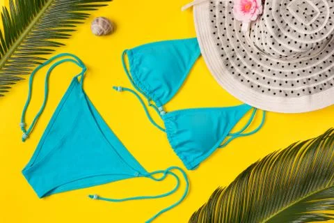Beach theme on the yellow background. Hat, palm leaves, swimsuit  on the yell Stock-Fotos