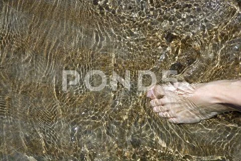 Beach tourist feet walking on shore shallow water Stock Photos