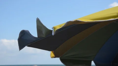 A beach umbrella develops in the wind on a sea beach 스톡 동영상 113993460