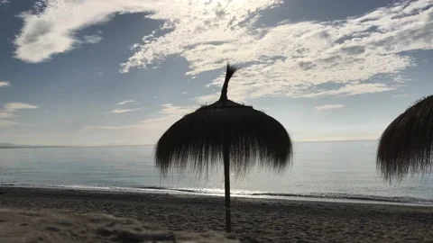 Beach umbrella made of straw on the sandy beach by mediterranean sea Stock Footage 132278477