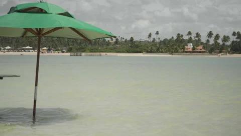 Beach umbrella in shallow water on cloudy day Stock Footage 232804627