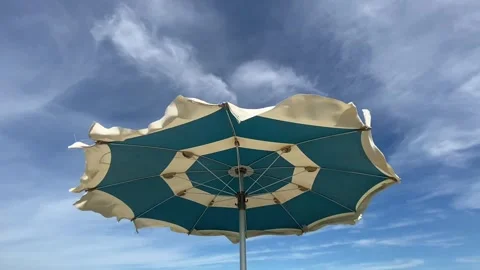 Beach umbrella vawing in the wind in a summer day. blue cloudy sky. Stock Footage 287099963