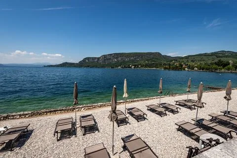 Beach Umbrellas and Empty Deck Chairs on Lake Garda - Veneto Italy Stock Photos