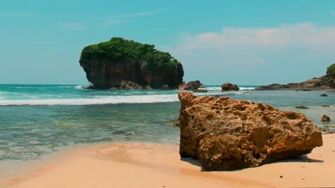 Beach view calm waves white sand blue water sky big rock sea shore coast line Видео 267345664