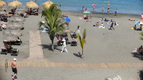 Beach visitors on volcanic sand in Costa Adeje Stock Footage 342481438