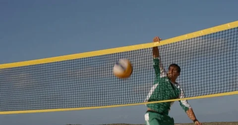 A Beach Volleyball player tips the ball over the net. Vídeo Stock 79822994