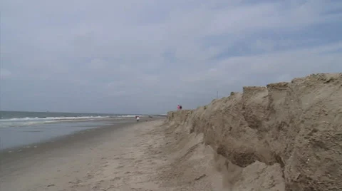 Beach walkers at eroding shoreline, sandy ridge - wide shot + pan Stock Footage 25847980