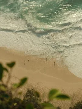 A beach with a wave crashing in the background Stock Photos