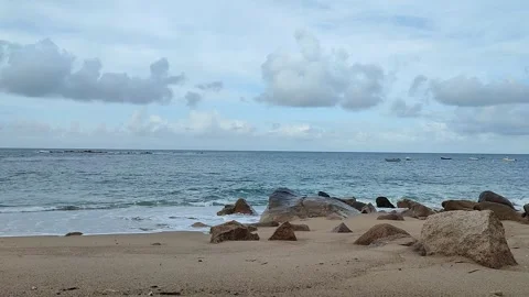 Beach with waves crashing, pebbles, big rocks and boats Stock Footage 276363858