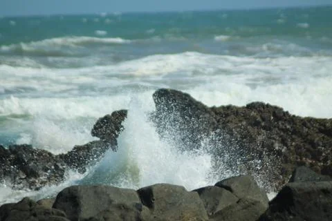 Beach waves hitting black rocks Stock Photos