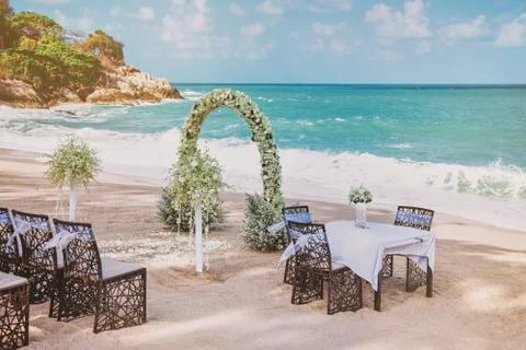 Beach wedding venue setting with flower decoration on arch, ocean background Fotos Stock