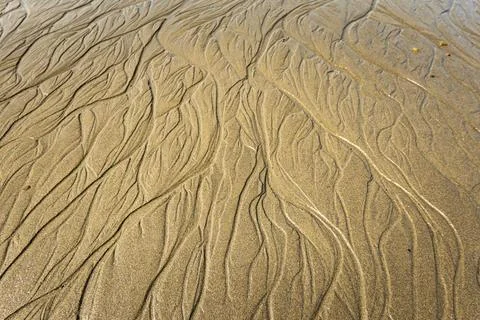 Beach, wet sand and the patterns made by waves or water.  sand pattern Stock Photos