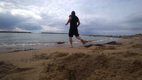 By the beach in winter with a man running into water Stock Footage 182276805
