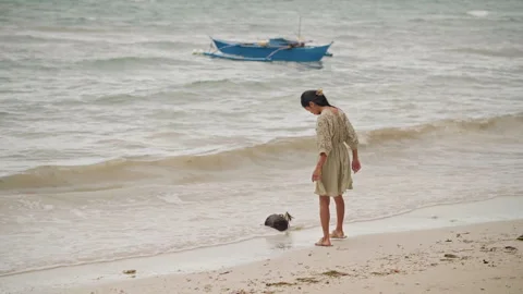 Beachcomber observing shoreline under cloudy sky. Asian woman discovers shells Stock Footage 341664546