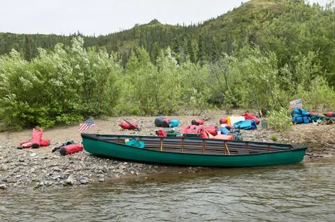 Beached canoe and gear drying on riverbank Foto stock