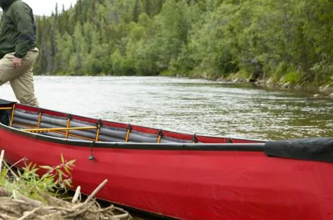 Beached, red inflatable canoe on river in Alaska Stock Photos