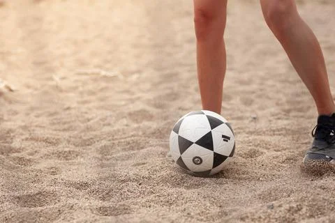 Beached soccer scene: a close view of a players legs and a patterned soccer Stock Photos