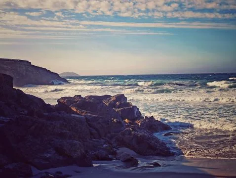 Beaches with waves and cliff at sunset on the Spanish coast Stock Photos