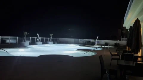 Beachfront hotel pool deck on windy night Stock Footage 243753875