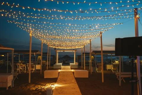 Beachfront Pathway with Twinkling String Lights at Sunset Stock Photos