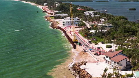 Beachfront Road and Seawall Construction Beside Green Tropical Water 스톡 동영상 346502287