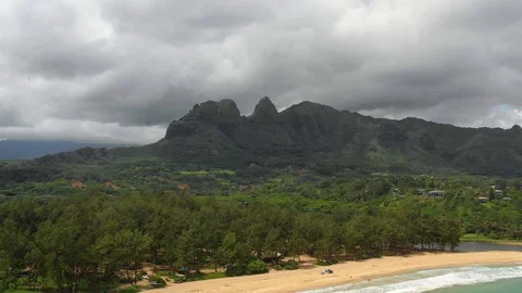 Beachgoers below a notched mountain ridge on Kauai Vídeos de archivo 96047284