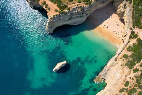 Beachgoers sunbathe while surrounded by limestone cliffs in the Algarve, Po.. Stock Photos