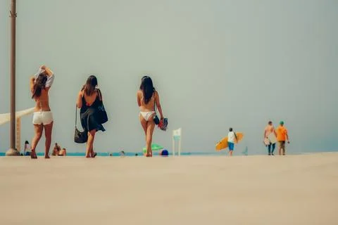 Beachgoers walking along a sunny seafront promenade Foto stock