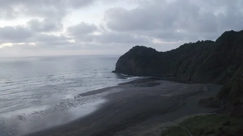 Beachside cliff at dusk. Aerial cloud and black sand beach. 4K Stock Footage 107407817