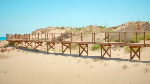 Beachside elevated wooden boardwalk with sandy grassland and blue sky Stock Footage 158299851